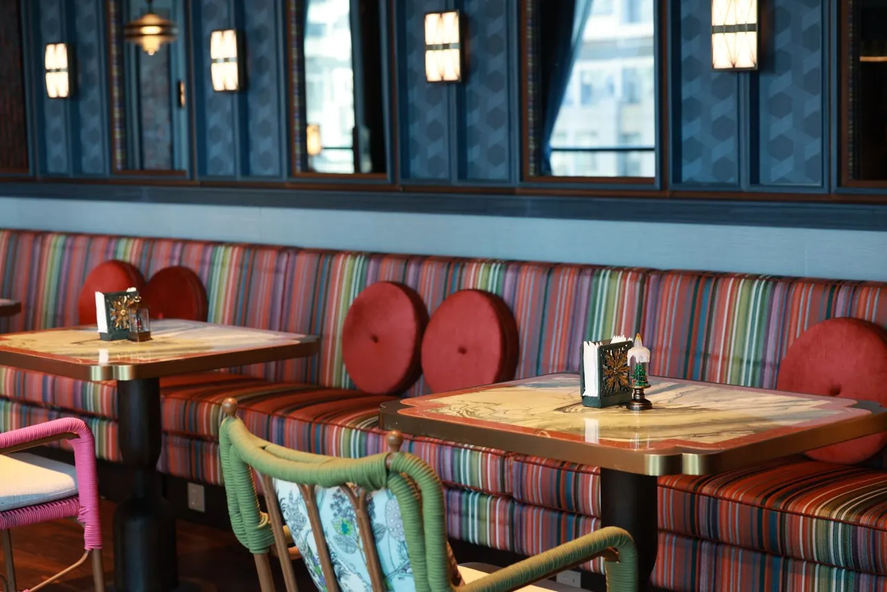 Interiér restaurace s čalouněnou lavicí, polštáři a sezením u stolů